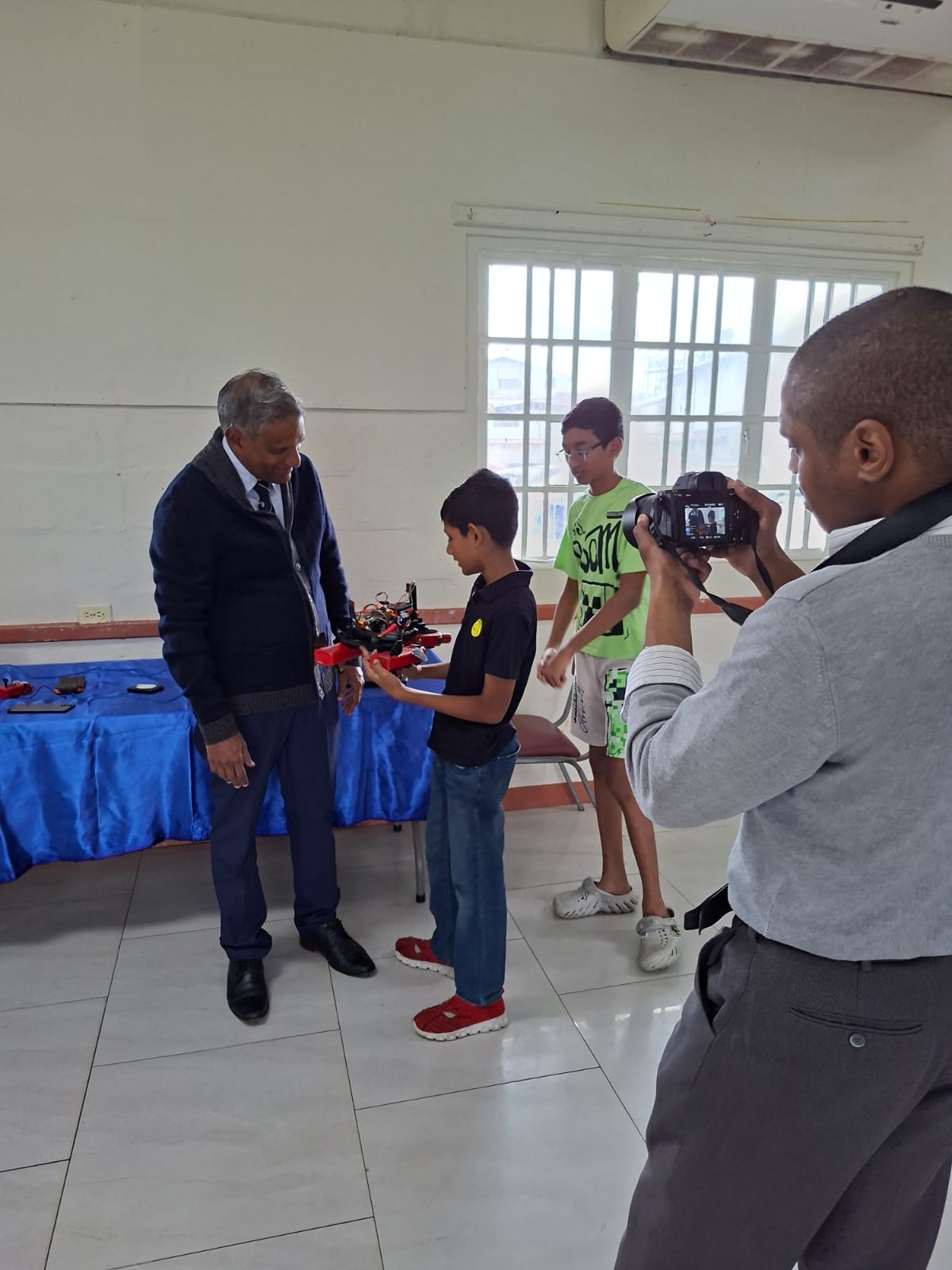 Student demonstrating a robot to a visitor while the team looks on